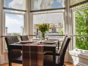 a dining room with a table and chairs and windows at Church View Apartment in Scarborough