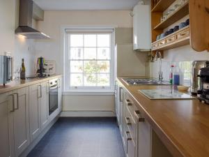 una cocina con armarios blancos y una ventana en The Cottage en Ledbury