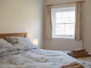 1 cama no hecha en un dormitorio con ventana en The Cottage en Ledbury