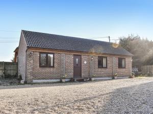 a small brick house on a gravel road at Honeypot Cottage in Maresfield