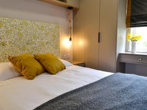 a bedroom with a bed with yellow pillows and a window at Kipp Away in Kippford