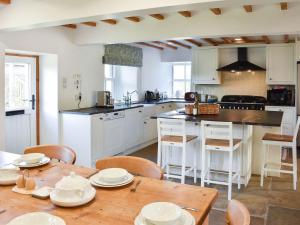 a kitchen with a wooden table with chairs and a kitchen with white cabinets at Southwaite in Outhgill