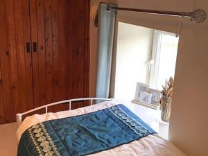 a bedroom with a bed with a blue blanket on it at Islas Cottage in Ystradgynlais