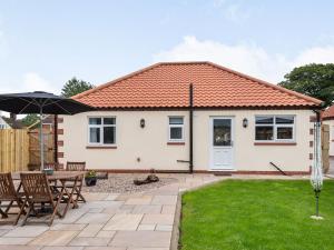 a cottage with a table and chairs and an umbrella at Sycamore Lodge in Chapel Saint Leonards