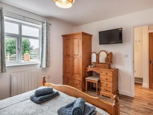 a bedroom with a bed and a desk and a television at Sycamore Lodge in Chapel Saint Leonards