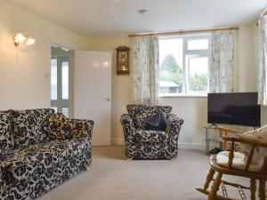 Llanferres的住宿－Sisial Y Gwynt，客厅配有沙发、椅子和电视