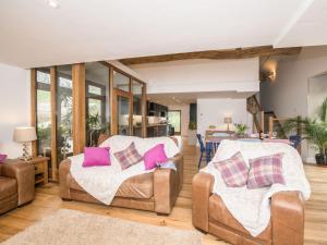 ein Wohnzimmer mit 2 Stühlen und rosa Kissen in der Unterkunft Harewood Barn in Brompton Regis