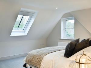 um quarto branco com uma cama com 2 janelas em The Old Stables 2 - Uk35616 em West Winterslow