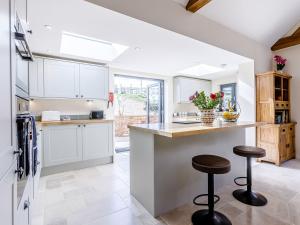 a kitchen with white cabinets and a counter with stools at The Old Dairy in Shipton under Wychwood
