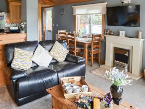 a living room with a leather couch and a table at Cairnswood in Swarland