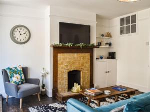 a living room with a fireplace and a clock at The Photographers House in Southwold