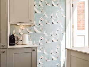 a kitchen with a bird wallpaper on the wall at The Photographers House in Southwold