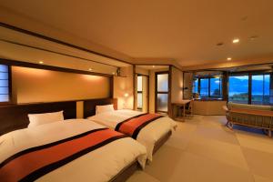 two beds in a hotel room with windows at Hayamakan in Kaminoyama