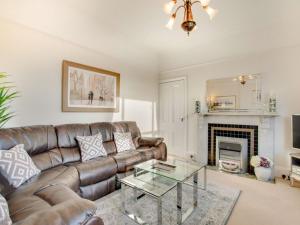 a living room with a leather couch and a fireplace at Kinbrae Apartment in Torquay