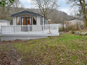 a small house with a porch and a white fence at The Hollies Lodge in Prenteg