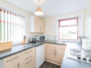 a kitchen with a counter top and two windows at Balnain 1 in Cononbridge