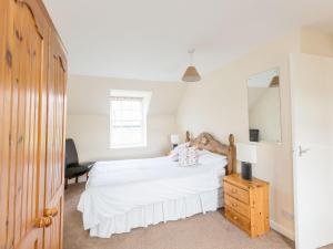 a bedroom with a white bed and a mirror at Balnain 1 in Cononbridge