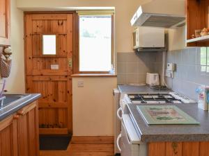 a kitchen with a sink and a stove top oven at Dairy Cottage - Uk37833 in Pillaton