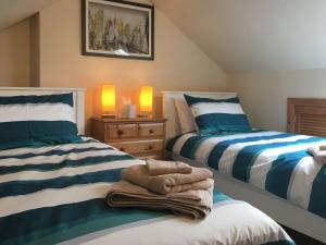 een slaapkamer met 2 bedden met blauwe en witte strepen bij Nidd Cottage in Pateley Bridge