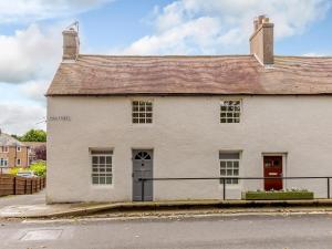 a white building with a red door on a street at Millers Cottage in Belford