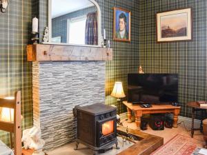 un salon avec une cheminée et une télévision dans l'établissement Balig Cottage, à Ballantrae