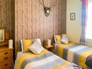 - une chambre avec 2 lits et une horloge murale dans l'établissement Balig Cottage, à Ballantrae