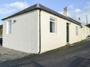 ein weißes Gebäude mit grüner Tür auf einer Straße in der Unterkunft Balig Cottage in Ballantrae
