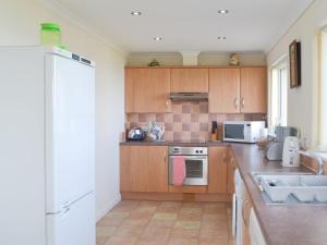 a kitchen with wooden cabinets and a white refrigerator at White Gables - Uk30688 in Portknockie