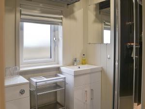 a white bathroom with a sink and a window at Merlins Cabin in Westward