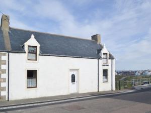 a white house with a black roof on a street at White Gables - Uk30688 in Portknockie