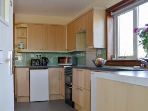 uma cozinha com armários de madeira e um frigorífico branco em Wester Links em Fortrose