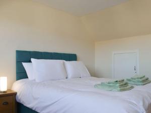 a white bed with a blue headboard and towels on it at Wester Links in Fortrose