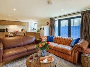 a living room with a brown leather couch and a table at Coach House Retreat - Uk32202 in Burton Bradstock