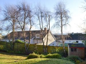 uma cerca num quintal com árvores e casas em Wester Links em Fortrose