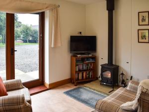 a living room with a fireplace and a television at Brooklands Cottage in Bellerby