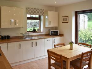 a kitchen with white cabinets and a wooden table at Brooklands Cottage in Bellerby