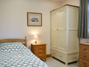 a bedroom with a bed and a tall cabinet at Brooklands Cottage in Bellerby