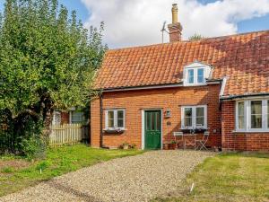 une maison en briques rouges avec une porte verte dans l'établissement Little Crown, à Winfarthing