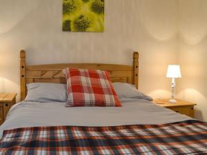 uma cama com um cobertor xadrez e duas almofadas em Isleport Lodge em Highbridge