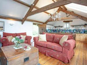 a living room with a red couch and a table at Higher Broadaford Barn in Ivybridge