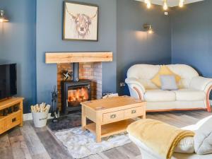 a living room with a fireplace and a couch at Broomlands Cottage in Beattock
