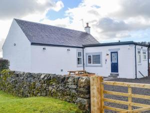 a white house with a stone fence in front of it at Broomlands Cottage in Beattock