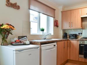 a kitchen with wooden cabinets and a sink and a window at Filey Central One - Uk31706 in Filey