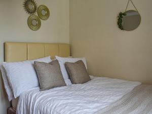 een bed met witte lakens en kussens in een slaapkamer bij Melody in Bowness-on-Windermere