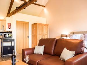 a living room with a leather couch and a bed at Hop Kiln Barn in Staunton on Wye