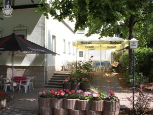 a patio with tables and chairs and umbrellas and flowers at Hotel Garni Melchendorf in Erfurt