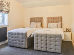 a bedroom with two beds with a large headboard at Kinneret Apartment in Silsden