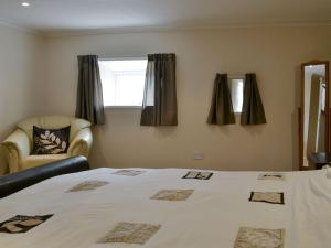 a bedroom with a bed and a chair and a window at Cobblestones in Westward