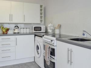 a white kitchen with a sink and a washing machine at Cotters Cottage - Uk10922 in Whithorn