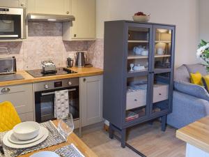 a kitchen with a blue cabinet with dishes in it at Little Ingas Cottage in Strathmiglo